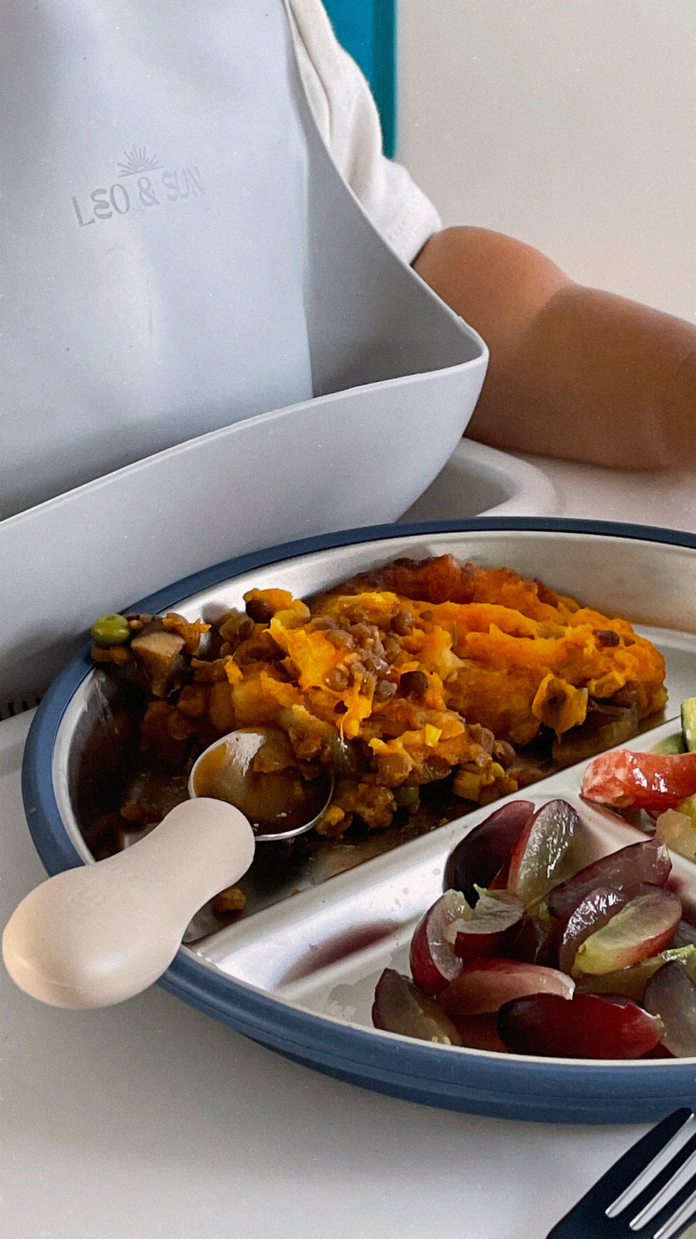 Plate of food with a spoon on a white surface, featuring a brand name.